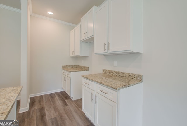 kitchen with light stone countertops, white cabinetry, light hardwood / wood-style flooring, and ornamental molding