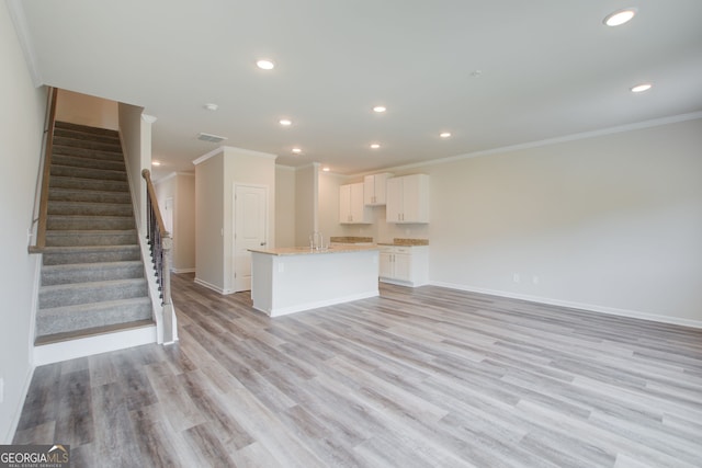 unfurnished living room with sink, crown molding, and light hardwood / wood-style floors