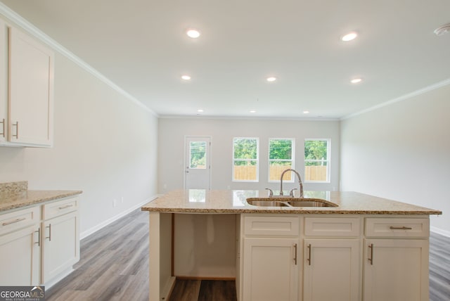 kitchen with light stone countertops, sink, white cabinets, and light hardwood / wood-style flooring