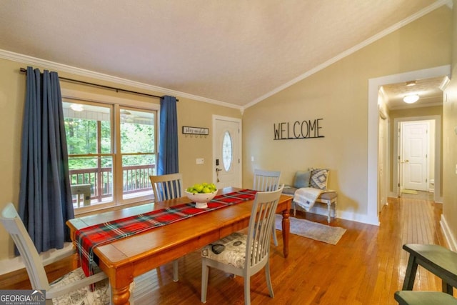 dining room featuring hardwood / wood-style flooring, lofted ceiling, and ornamental molding