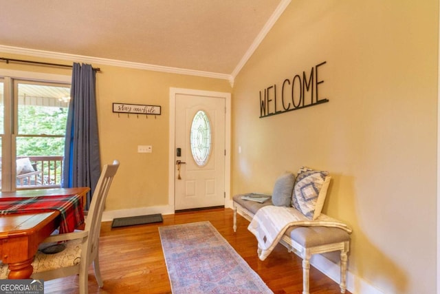 foyer with hardwood / wood-style floors, a healthy amount of sunlight, lofted ceiling, and crown molding