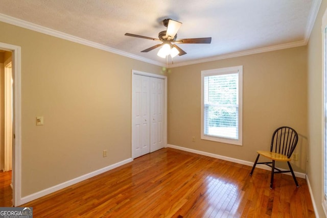 unfurnished bedroom with hardwood / wood-style floors, a closet, ornamental molding, and ceiling fan