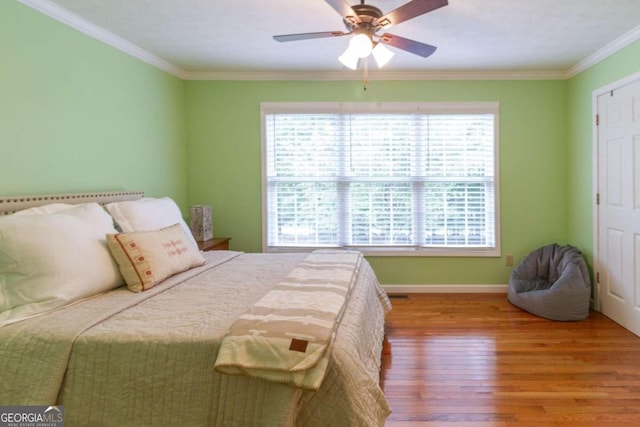 bedroom featuring ceiling fan, wood-type flooring, and ornamental molding