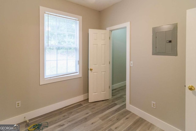 empty room with electric panel and light hardwood / wood-style floors