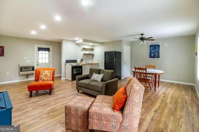 living room featuring light wood-type flooring, heating unit, and ceiling fan