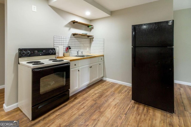 kitchen featuring wood counters, black refrigerator, tasteful backsplash, white electric range oven, and white cabinetry