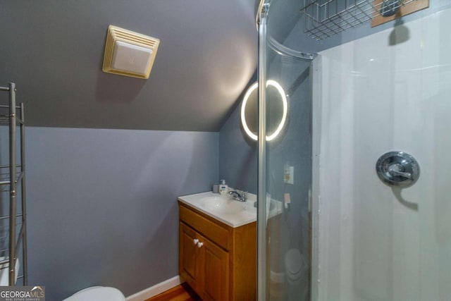 bathroom with toilet, vanity, vaulted ceiling, and a shower with shower door