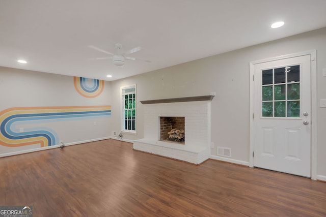 unfurnished living room featuring dark hardwood / wood-style floors, ceiling fan, and a fireplace