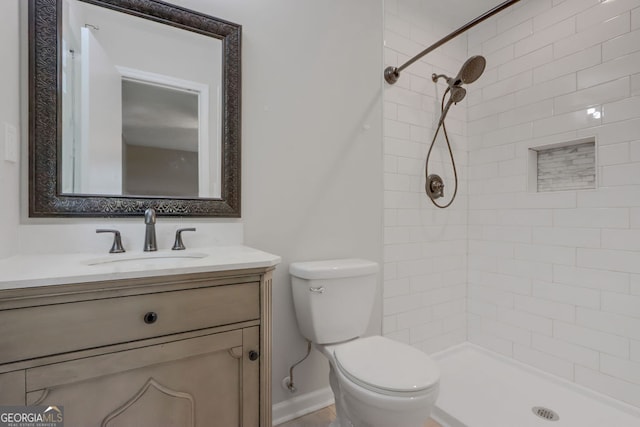 bathroom featuring tiled shower, toilet, and vanity with extensive cabinet space