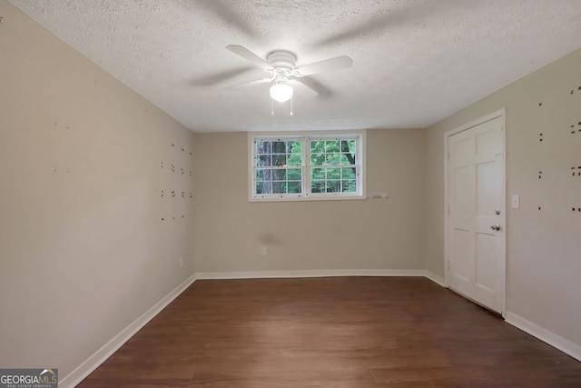 empty room featuring a textured ceiling, dark hardwood / wood-style floors, and ceiling fan