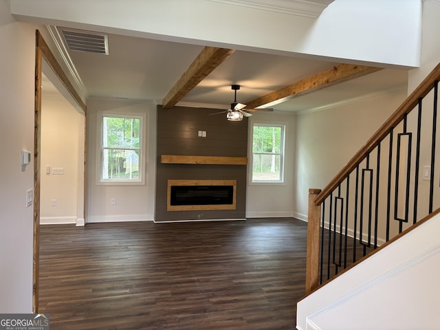 unfurnished living room featuring stairway, a wealth of natural light, dark wood-style flooring, and visible vents