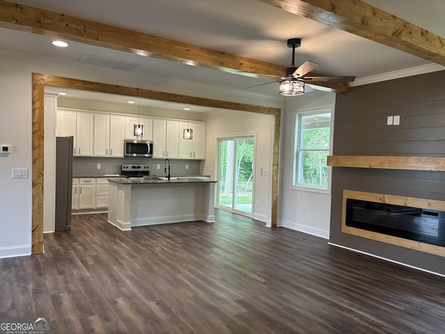 kitchen with appliances with stainless steel finishes, a sink, open floor plan, baseboards, and beamed ceiling