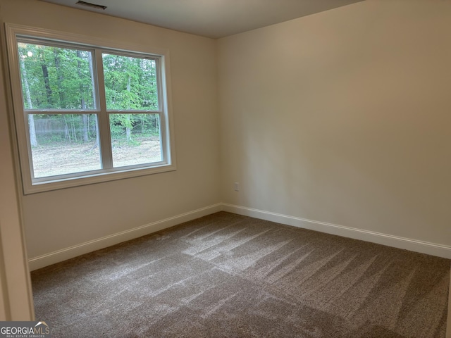 unfurnished room featuring baseboards, dark carpet, and visible vents