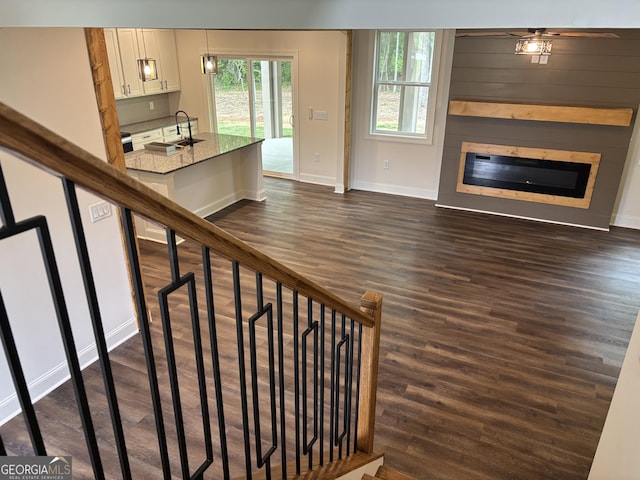 stairs featuring a glass covered fireplace, baseboards, and wood finished floors