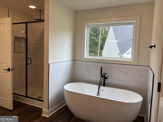 bathroom featuring a soaking tub, tile walls, wood finished floors, and a stall shower