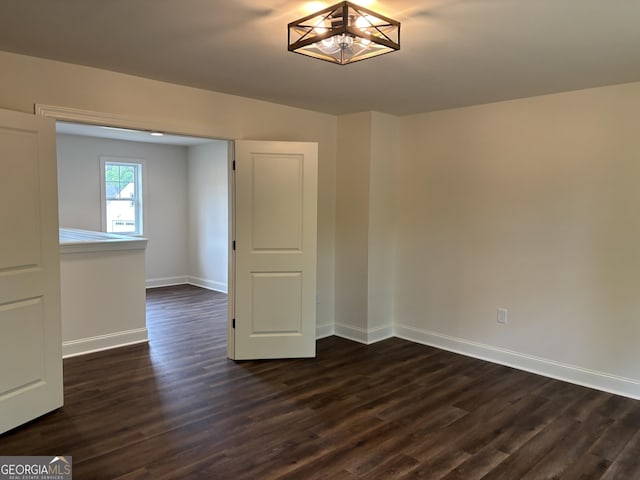 empty room with baseboards and dark wood-style floors