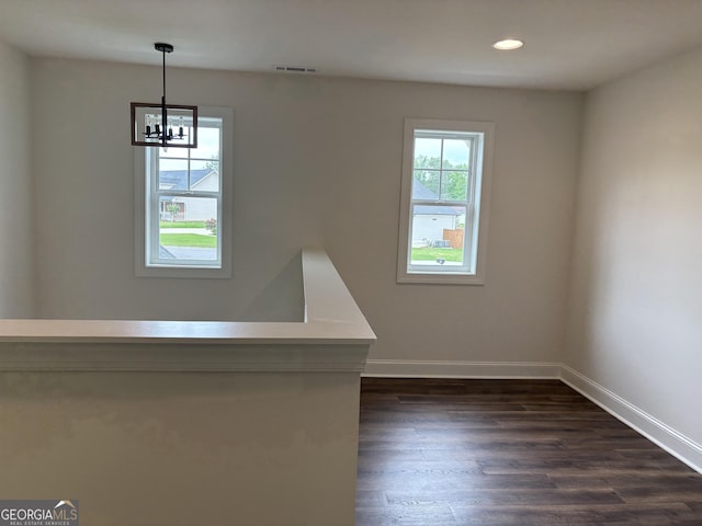 empty room featuring dark wood-style flooring, a notable chandelier, recessed lighting, baseboards, and visible vents