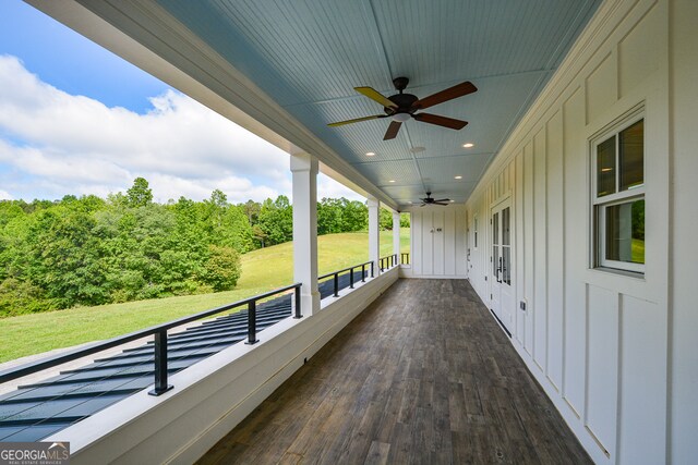 wooden terrace featuring ceiling fan and a lawn