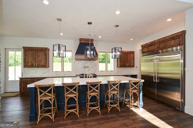 kitchen with dark hardwood / wood-style flooring, plenty of natural light, tasteful backsplash, a center island, and stainless steel built in fridge