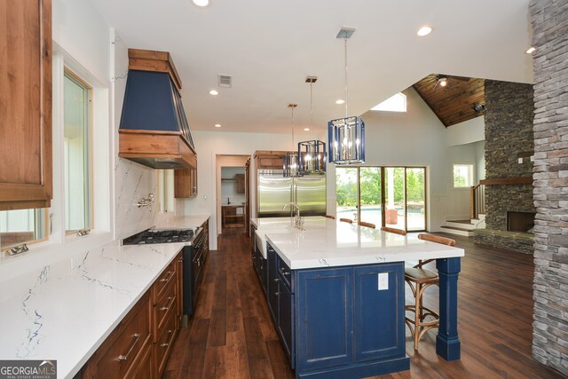 kitchen with custom range hood, a fireplace, a center island with sink, premium appliances, and dark wood-type flooring