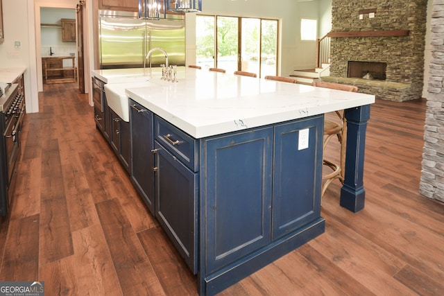 kitchen featuring a center island with sink, a fireplace, and dark hardwood / wood-style floors