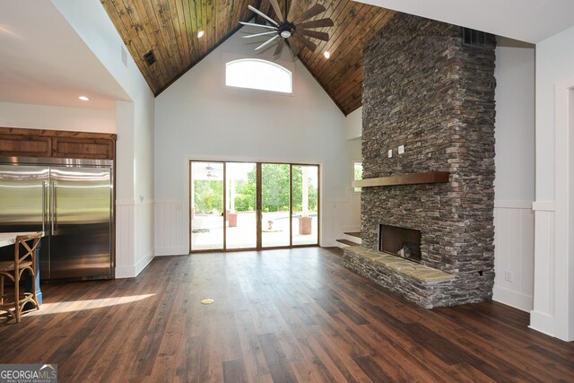 unfurnished living room featuring dark hardwood / wood-style floors, high vaulted ceiling, and a stone fireplace