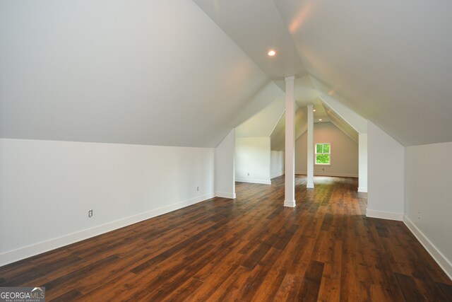 additional living space with dark wood-type flooring and vaulted ceiling