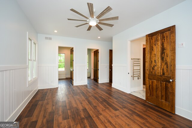 unfurnished bedroom featuring connected bathroom, dark hardwood / wood-style floors, and ceiling fan