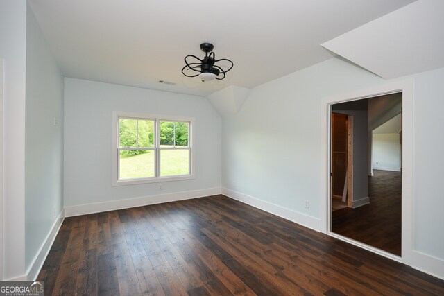 unfurnished room with vaulted ceiling and dark wood-type flooring