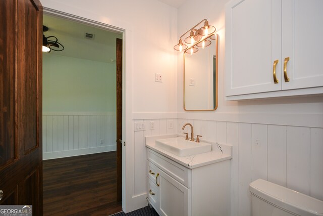 bathroom with vanity with extensive cabinet space, toilet, and wood-type flooring