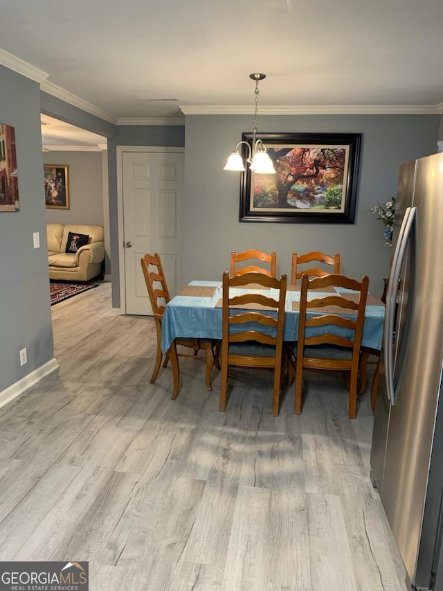 dining room with light hardwood / wood-style floors, crown molding, and a chandelier