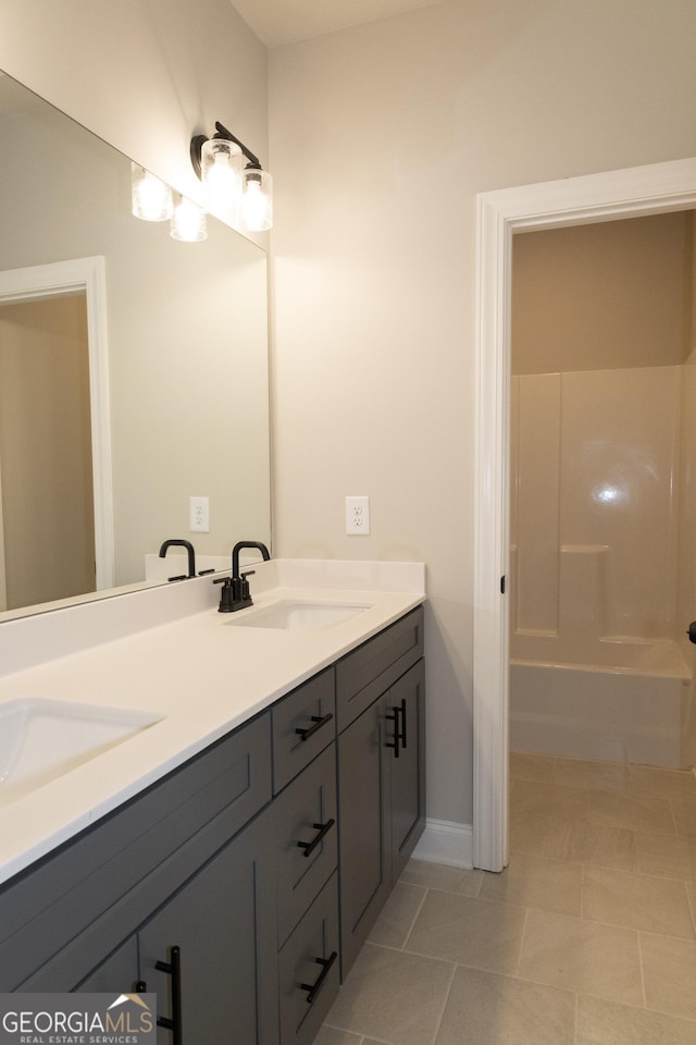 full bathroom with double vanity, baseboards, and a sink