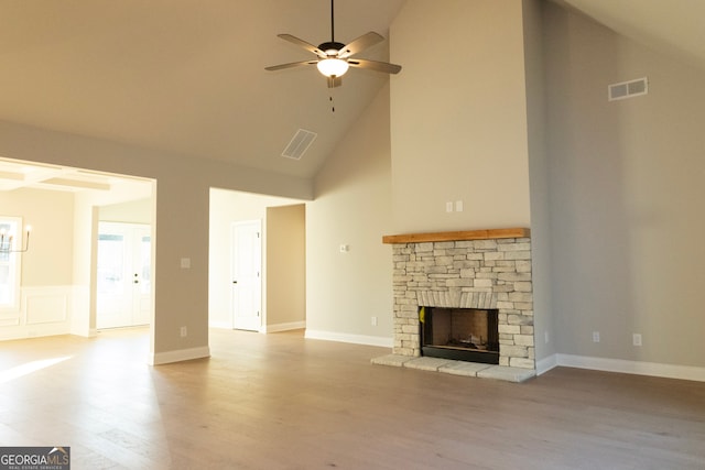 unfurnished living room featuring a stone fireplace, ceiling fan, high vaulted ceiling, and light hardwood / wood-style floors