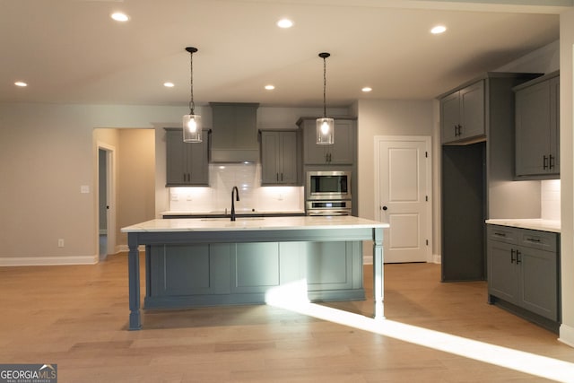 kitchen featuring decorative backsplash, light hardwood / wood-style flooring, a kitchen island with sink, and gray cabinetry