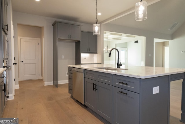 kitchen with an island with sink, appliances with stainless steel finishes, light stone counters, pendant lighting, and a sink