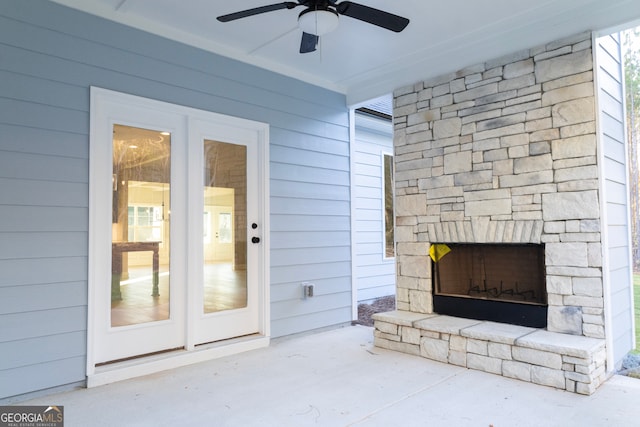 living room with wooden walls, ceiling fan, concrete floors, and an outdoor stone fireplace