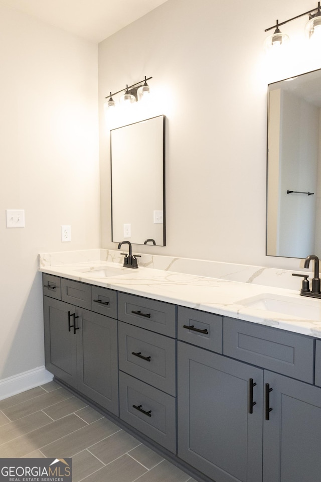 bathroom with a sink, baseboards, and double vanity