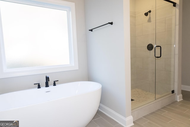 bathroom featuring a shower stall, baseboards, and a freestanding bath