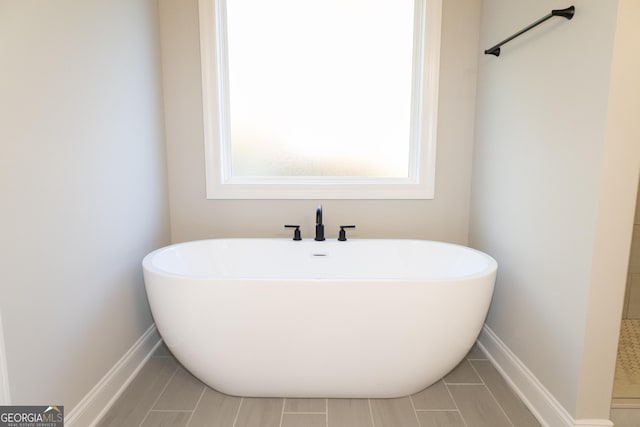 full bathroom with baseboards and a freestanding bath