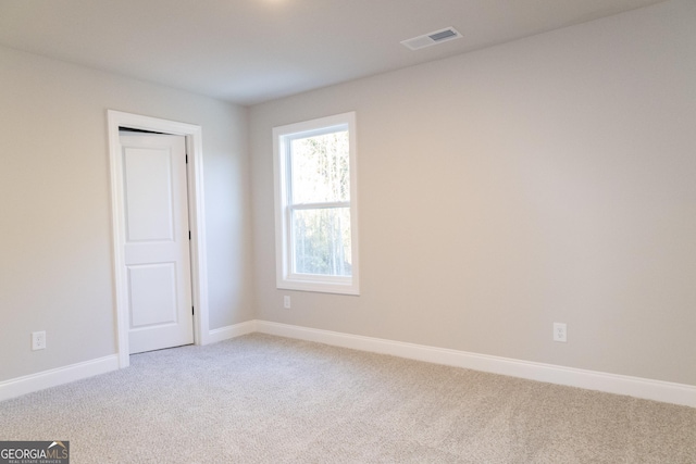 unfurnished room featuring light colored carpet, visible vents, and baseboards