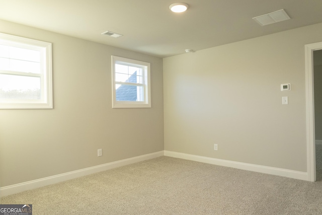 empty room featuring light carpet, visible vents, and baseboards