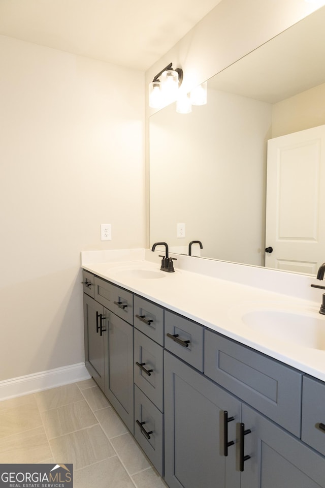 full bath with a sink, baseboards, and double vanity