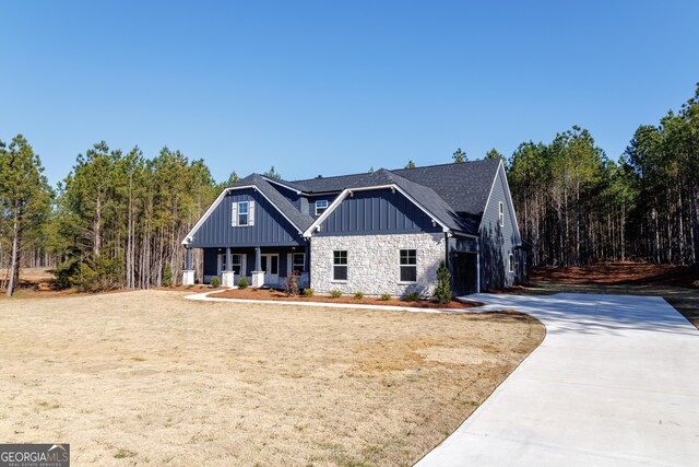 view of front of property featuring a porch, a garage, and a front lawn