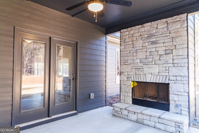 entrance to property with stone siding, an outdoor stone fireplace, and a ceiling fan