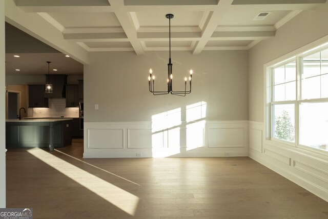 unfurnished dining area featuring hardwood / wood-style flooring, a wealth of natural light, and coffered ceiling