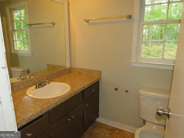 bathroom with toilet, tile patterned flooring, a healthy amount of sunlight, and vanity