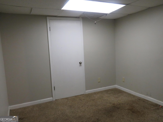 carpeted empty room featuring a drop ceiling