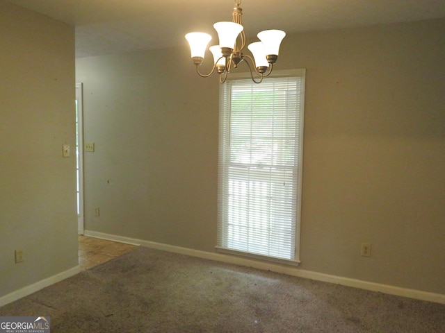 carpeted empty room featuring a chandelier