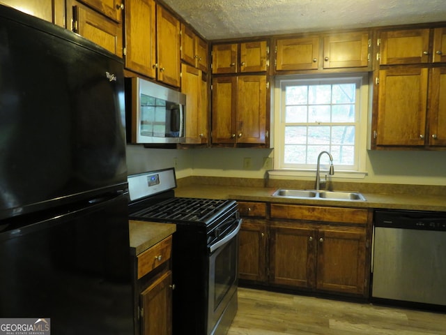 kitchen featuring light hardwood / wood-style floors, sink, a textured ceiling, and appliances with stainless steel finishes