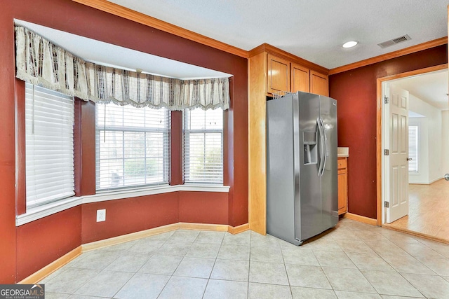 kitchen with stainless steel refrigerator with ice dispenser, light tile flooring, and crown molding